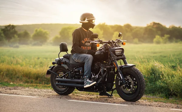 Байкер сидит на мотоцикле Harley Davidson Fat Bob 114 2020 в поле рядом с трассой. Харьков, Украина-15 июля 2021 года. — стоковое фото