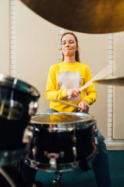La ragazza suona il drum kit diligentemente. — Foto Stock
