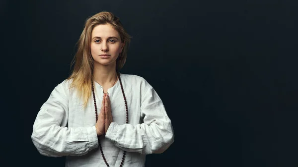 Retrato de una mujer yogui haciendo namaste mudra sobre un fondo negro. — Foto de Stock