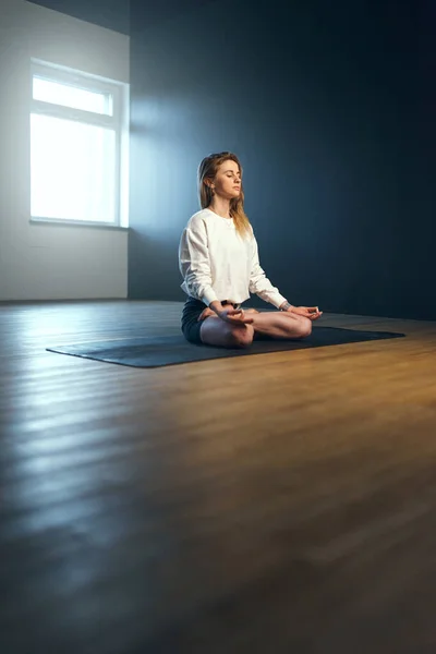 Young woman sitting in pranayama with jnana mudra. Yoga practice in the studio. — Stock Photo, Image
