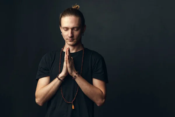 Retrato de un hombre yogui haciendo namaste sobre un fondo negro. — Foto de Stock