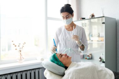 Güzellik uzmanı kadının yüzündeki kozmetik enjeksiyonunu gösteriyor. Kozmetik Yaşlanma Karşıtı İşlem Hazırlığı.