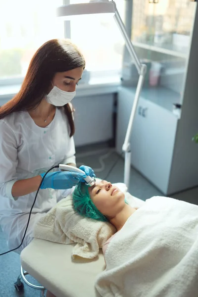 Косметолог проводит косметическую процедуру с ультразвуковым фонофорезом. — стоковое фото