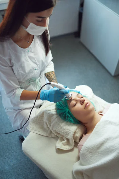 Профессиональный косметолог проводит ультразвуковую фонофорез для молодой женщины. — стоковое фото