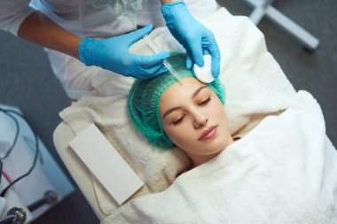 Güzellik uzmanı genç bir kızın yüzüne kozmetik dolguları enjekte ediyor..