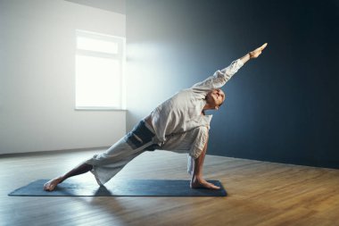 Yogi adam utthita parsvakonasana yapıyor. Stüdyoda yoga çalışması..