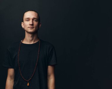 Siyah arka planda boynunda tespih olan Yogi bir adam..