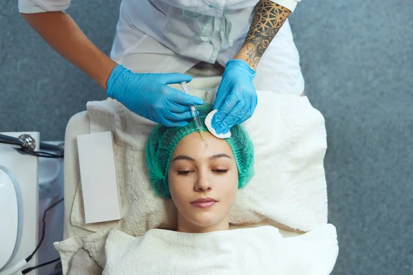 Молодая девушка лежит на косметологическом столе для инъекций красоты, антивозрастного косметического лечения. — стоковое фото