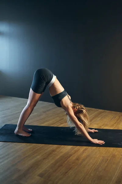 Woman doing adho mukha svanasana. Yoga practice in the studio. — Stock Photo, Image