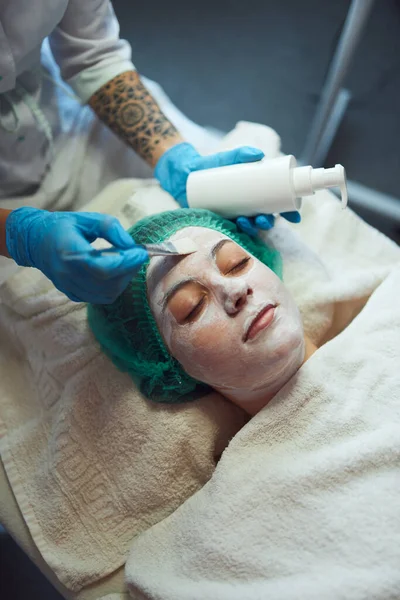 Ansikte peeling mask, spa skönhetsbehandling, hudvård. Kvinnan får ansiktsvård av kosmetolog på skönhetssalong. — Stockfoto