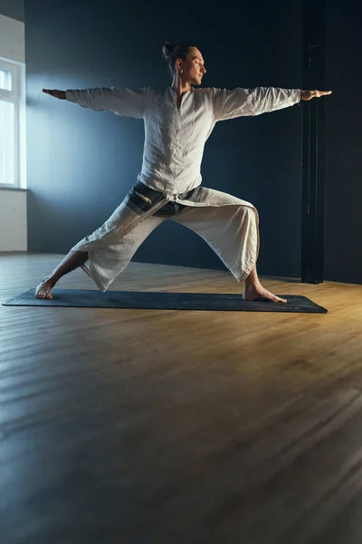 Yogi man doing warrior two pose. Yoga practice in the studio.
