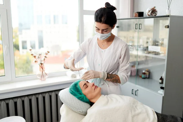 Beautician lleva a cabo la inyección de mesoterapia para la mujer. Procedimiento de rejuvenecimiento cosmetológico. Imagen de stock