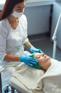 Güzellik uzmanı genç bir kızın yüzünü soyuyor. Kozmetolojik işlem.