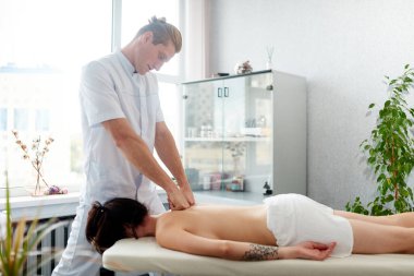 Profesyonel terapist masörü genç bir kıza yumruklarıyla masaj yapıyor. Sağlık merkezinde vücut masajı yapıyorum..