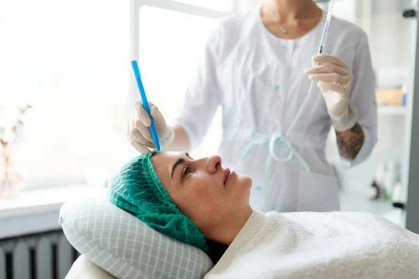 Косметолог набирает очки за инъекцию красоты на лице женщины. Подготовка к косметической антивозрастной процедуре. — стоковое фото