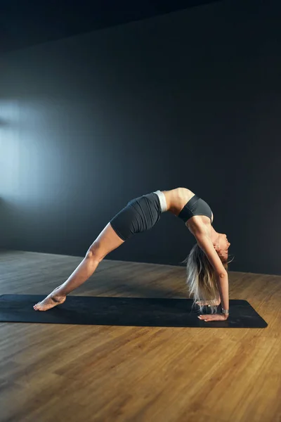 Woman doing urdhva dhanurasana pose. Yoga practice in the studio. — Stock Photo, Image