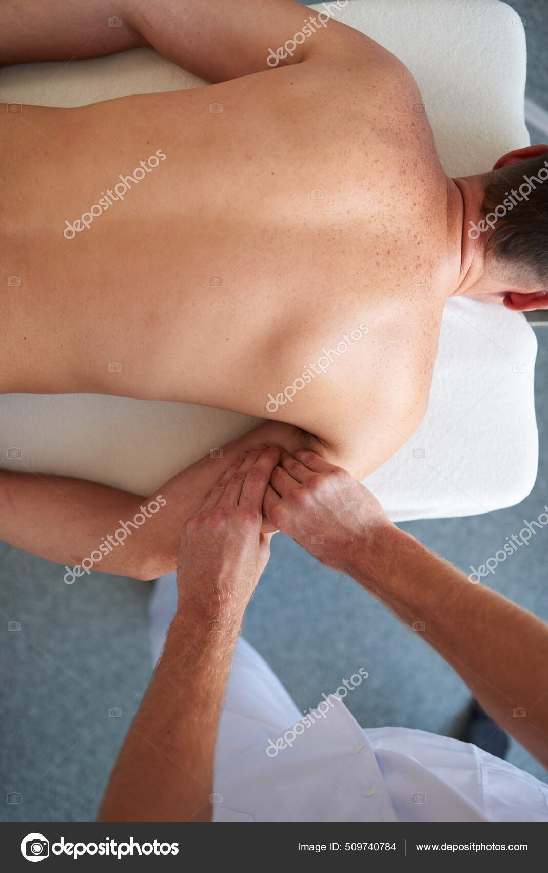 A man therapist massages the shoulder of a young girl. Massage therapy the  medical center. Stock Photo by Artranq