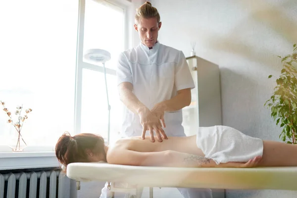 Recepción en el masajista. El masajista da un masaje de espalda médica para una joven. — Foto de Stock