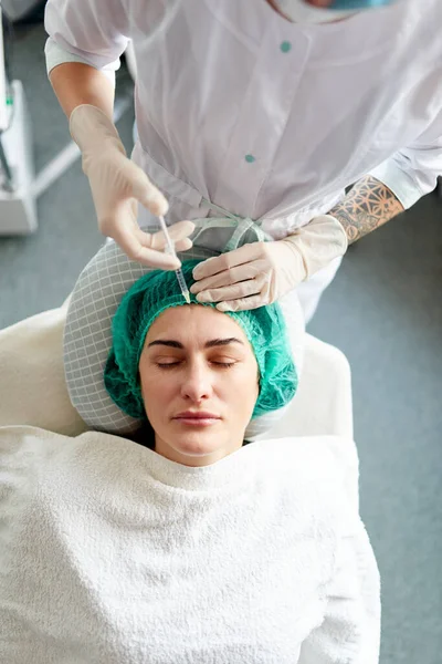 Un cosmetólogo inyecta preparación cosmética de rejuvenecimiento en una cara de mujer. Procedimiento contra el envejecimiento de la cosmetología. — Foto de Stock