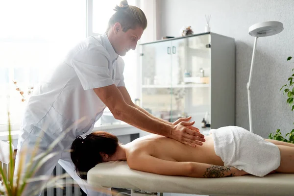 Un terapeuta profesional hace un masaje terapéutico de los pacientes de vuelta. Masaje corporal curativo en el centro médico. — Foto de Stock
