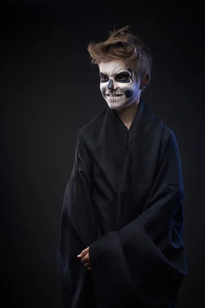 Teen with make-up of skull in black cloak laughs — Stock Photo, Image