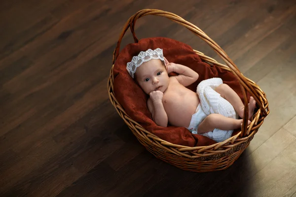 Newborn with a crown in  basket on  floor — Stock Photo, Image