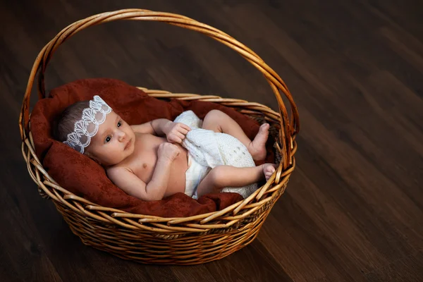 Newborn with a crown in  basket on  floor — Stock Photo, Image