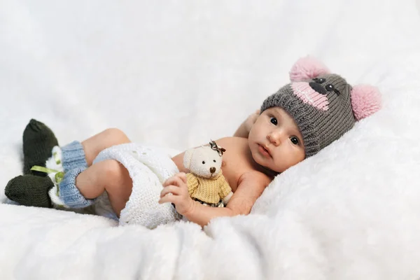 Newborn baby with teddy bear in a knitted hat — Stock Photo, Image