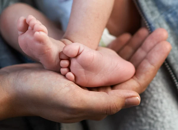 Mom keeps  miniature newborn leg in hand — Stock Photo, Image