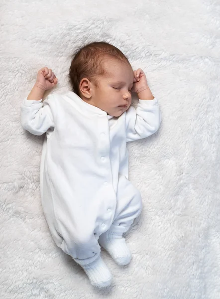 Nyfødt barn som sover på hvit pels i sollys – stockfoto