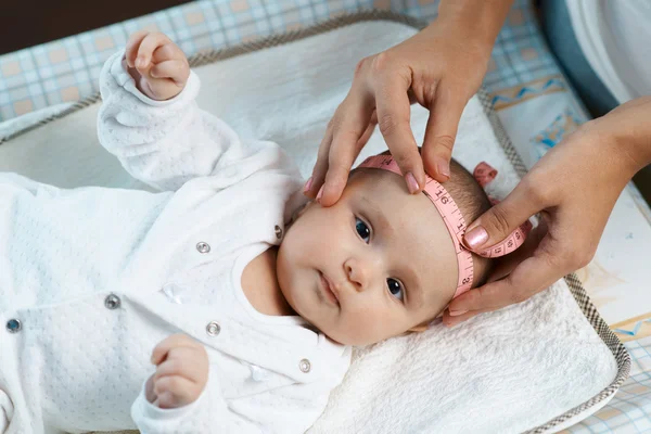 Terapeuta mide tamaño cabeza de hermoso bebé —  Fotos de Stock
