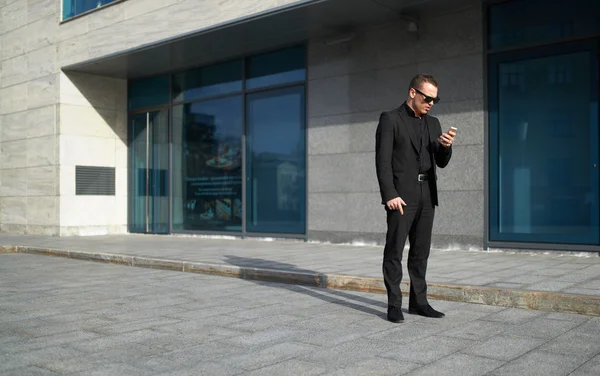 Business man looking to phone near office — стоковое фото