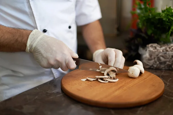Lo chef taglia funghi su una tavola di legno — Foto Stock