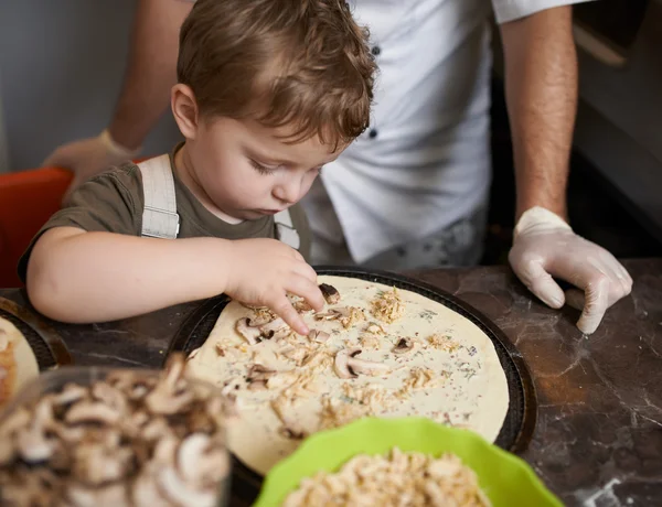 Ragazzo mette ingredienti per la pizza — Foto Stock