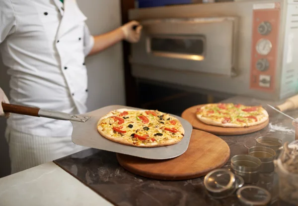 Chef coloca na mesa pizza preparada na hora — Fotografia de Stock