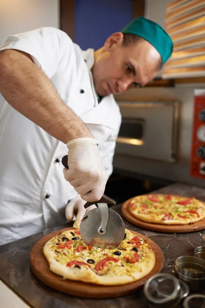 Chef-kok snijdt vers bereide pizza — Stockfoto