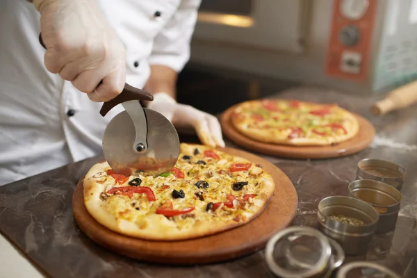 Chef corta fatias de pizza na hora — Fotografia de Stock