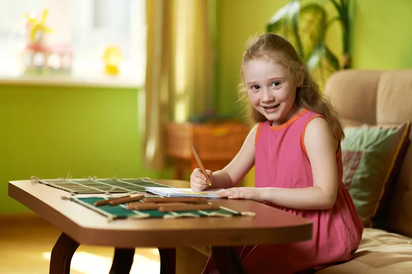 Menina desenha lápis sobre papel à mesa — Fotografia de Stock