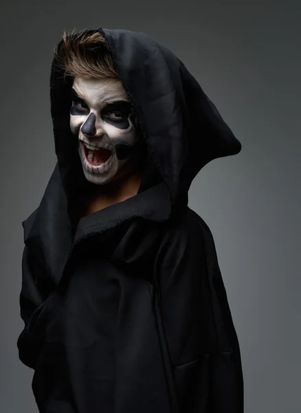 Teen with make-up of the skull in a black cloak laughs — Stock Photo, Image