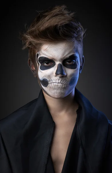 Teen with make-up of the skull in a black cloak unhappy — Stock Photo, Image