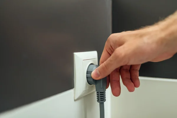 Man arm put jack into plug in the room — Stock Photo, Image