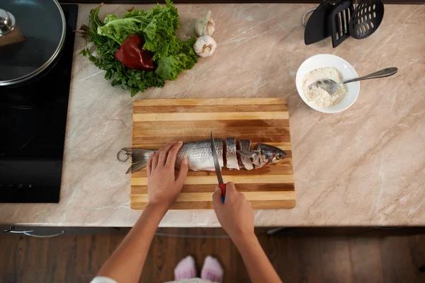 Girl cut slice of  fish to cook dinner — Stock Photo, Image