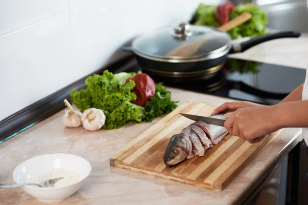 Girl cut slice of  fish to cook tasty dish — Stock Photo, Image