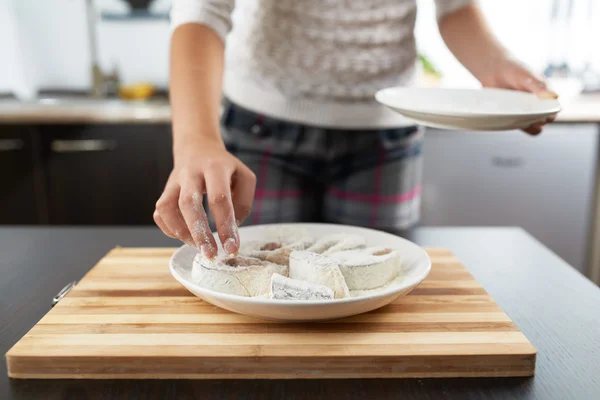 Jenta ruller fisk i mel for å steke – stockfoto