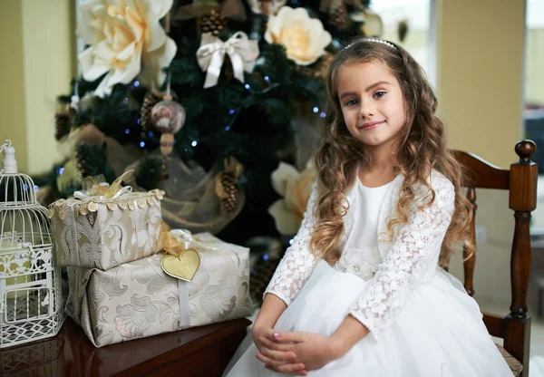 漂亮的女孩正坐在靠近圣诞树用的礼物 — 图库照片