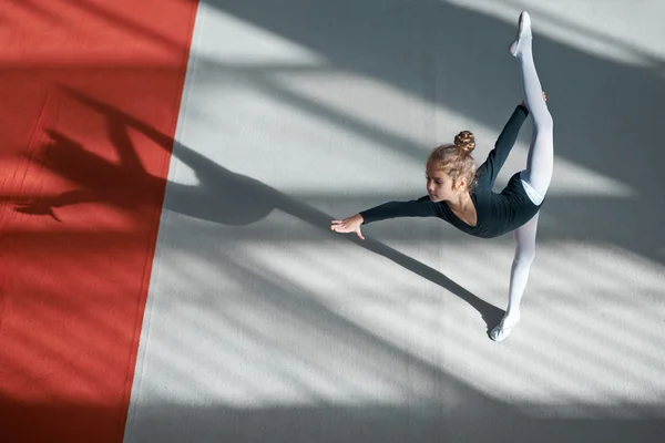 Девушка делает баланс в зале художественной гимнастики — стоковое фото