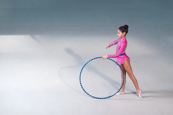 Gimnasta en un traje rosa haciendo ejercicio de aro — Foto de Stock