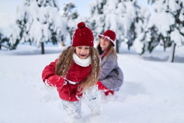 Anne ile kızı karla kaplı parkta oynamak 