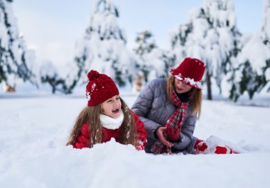 Anne ile kızı karla kaplı parkta oynamak 