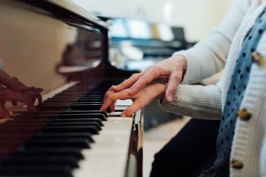 müzik öğretmeni öğrencinin doğru oynamak için yardımcı olur.